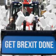 DEPARTURE: Prime Minister Boris Johnson drives a Union flag-themed JCB through a fake wall emblazoned with the word 