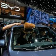 A worker wipes as visitors sit on a BYD Song Pro DM-i car model during the Auto China 2024 in Beijing (Andy Wong/AP)