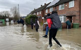People wade through flood water in Loughborough (Callum Parke/PA).